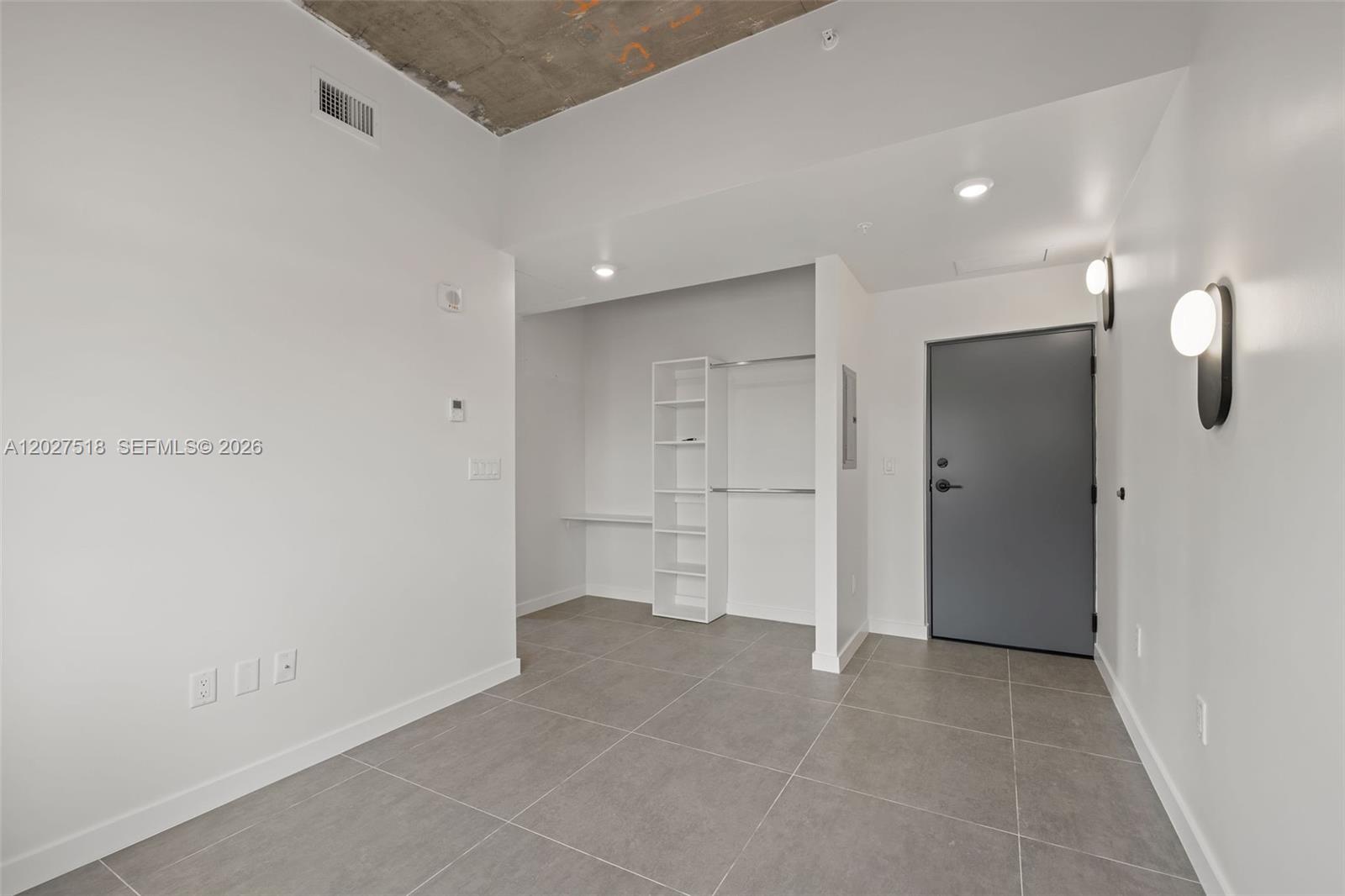 A room with gray tile flooring, white walls, an open closet, and a gray door — 315 NW 32 ST # 305, Miami FL 33127, MIAMI, FL