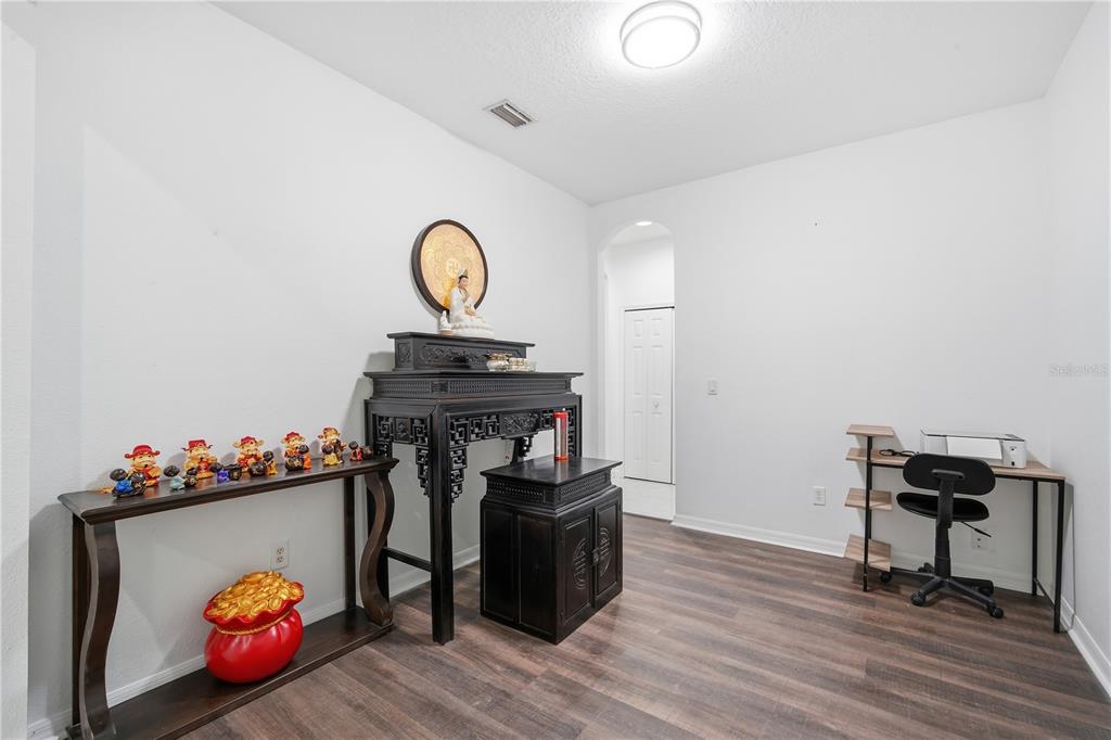 A room with wood-look flooring features a traditional wooden altar and a small desk — 9821 JASMINE BROOK CIRCLE, LAND O LAKES, FL