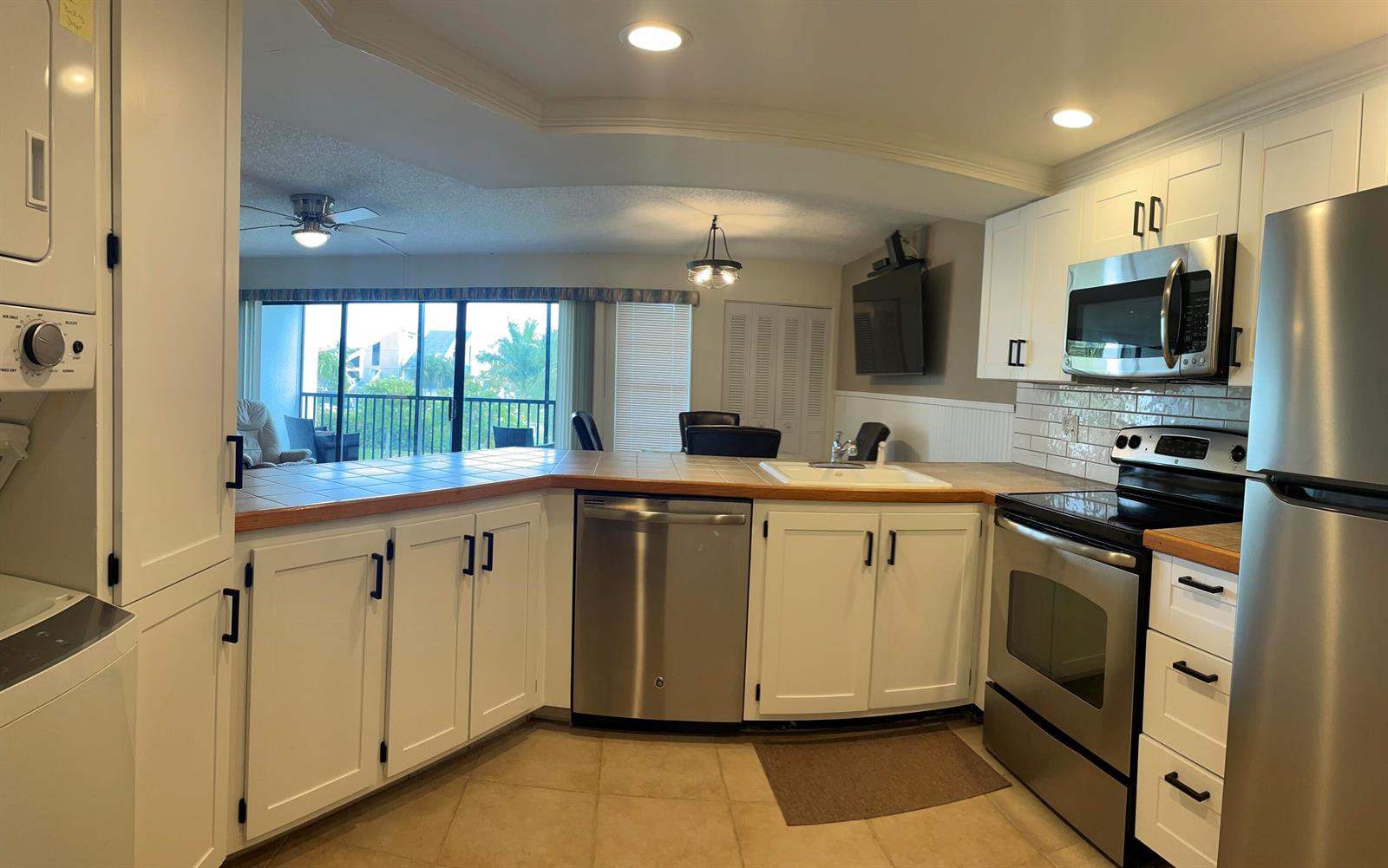 A kitchen with white cabinets, stainless steel appliances, and a tiled countertop overlooks a dining area — 1605 S Us Highway 1, Jupiter FL 33477, JUPITER, FL