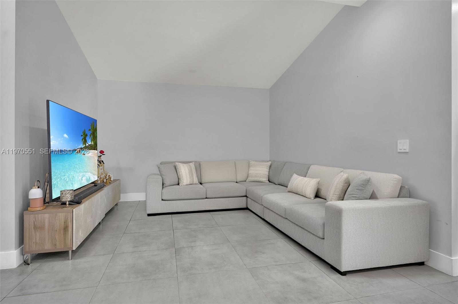 A living room features a light gray sectional sofa, a television on a console, and tile flooring — 17032 NW 63rd Pl, Hialeah FL 33015, HIALEAH, FL