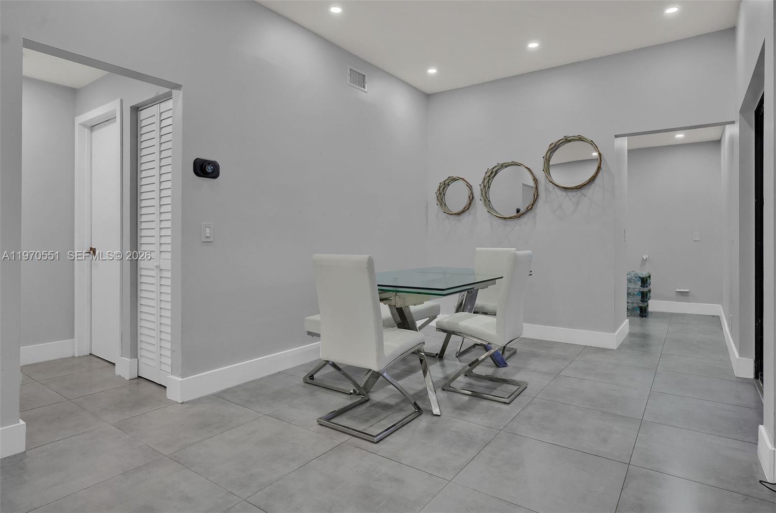 A dining area features a glass-topped table, four white chairs, and gray tile flooring — 17032 NW 63rd Pl, Hialeah FL 33015, HIALEAH, FL