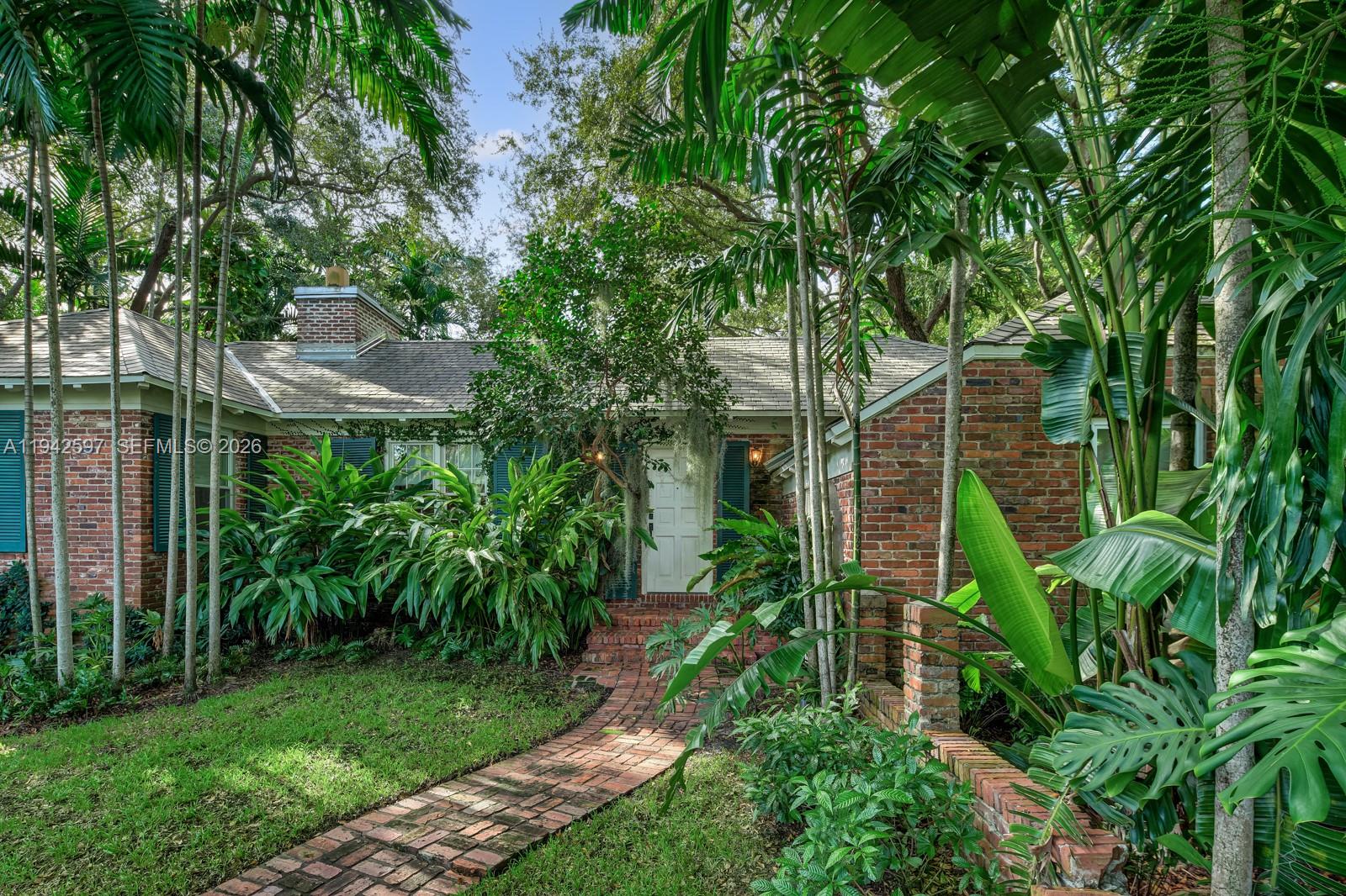 A brick house with a brick walkway and lush tropical landscaping in the front yard — 530 Melaleuca Ln, Miami FL 33137, MIAMI, FL
