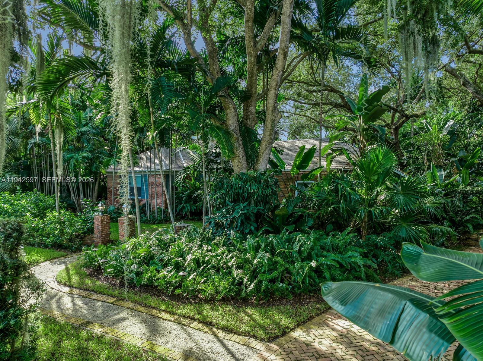 A brick house is partially obscured by lush tropical landscaping and large trees — 530 Melaleuca Ln, Miami FL 33137, MIAMI, FL