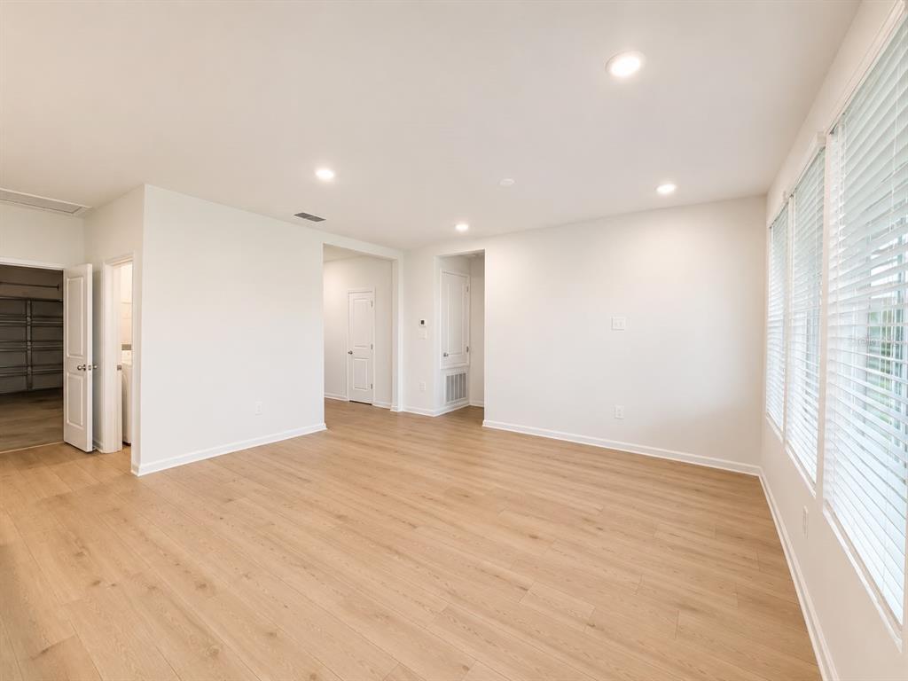 An empty room with light wood-look flooring, white walls, and large windows with white blinds — 817 HOUSE BOULEVARD, HAINES CITY, FL