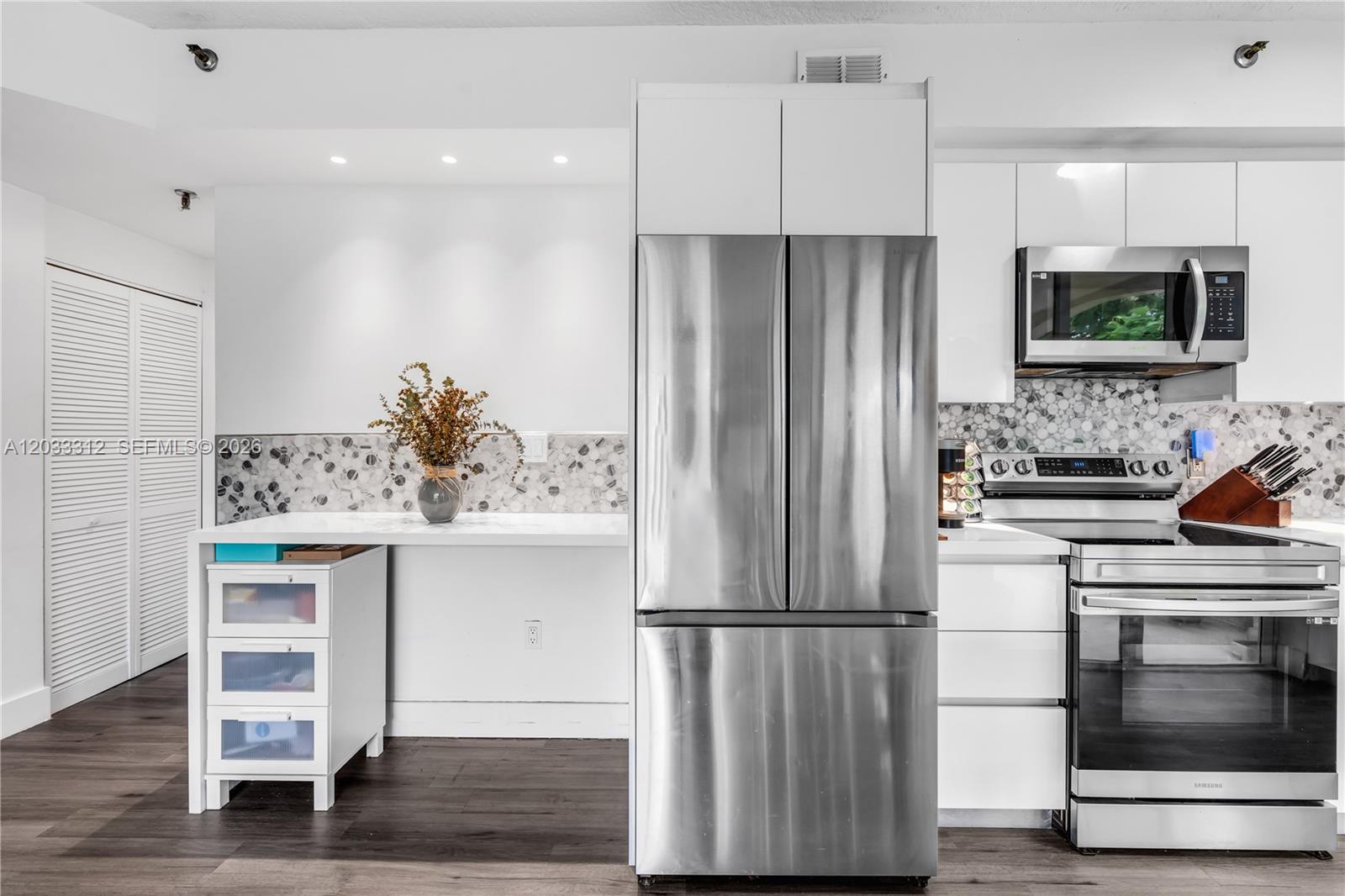 A modern kitchen features white cabinetry, stainless steel appliances, and a mosaic tile backsplash — 1834 Brickell Ave # 33, Miami FL 33129, MIAMI, FL
