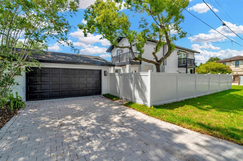 A white two-story house with a black garage door and a white vinyl privacy fence — 4902 W SAN RAFAEL STREET, TAMPA, FL