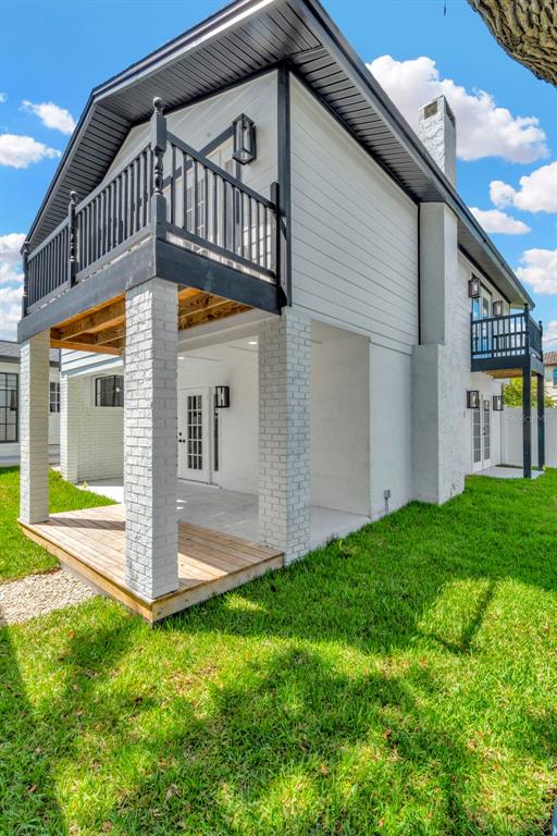A two-story house exterior features white brick pillars, a wooden deck, and black balcony railings — 4902 W SAN RAFAEL STREET, TAMPA, FL
