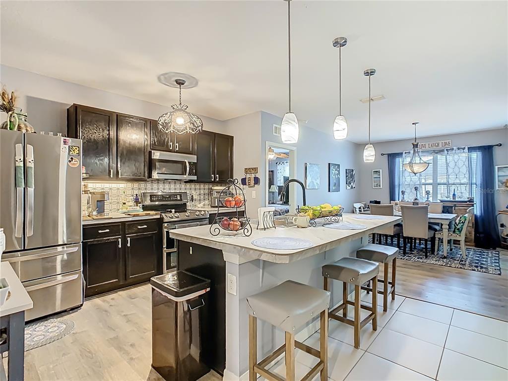 A kitchen with dark cabinets, a central island with bar seating, and an adjacent dining area — 1765 BROCKRIDGE ROAD, KISSIMMEE, FL