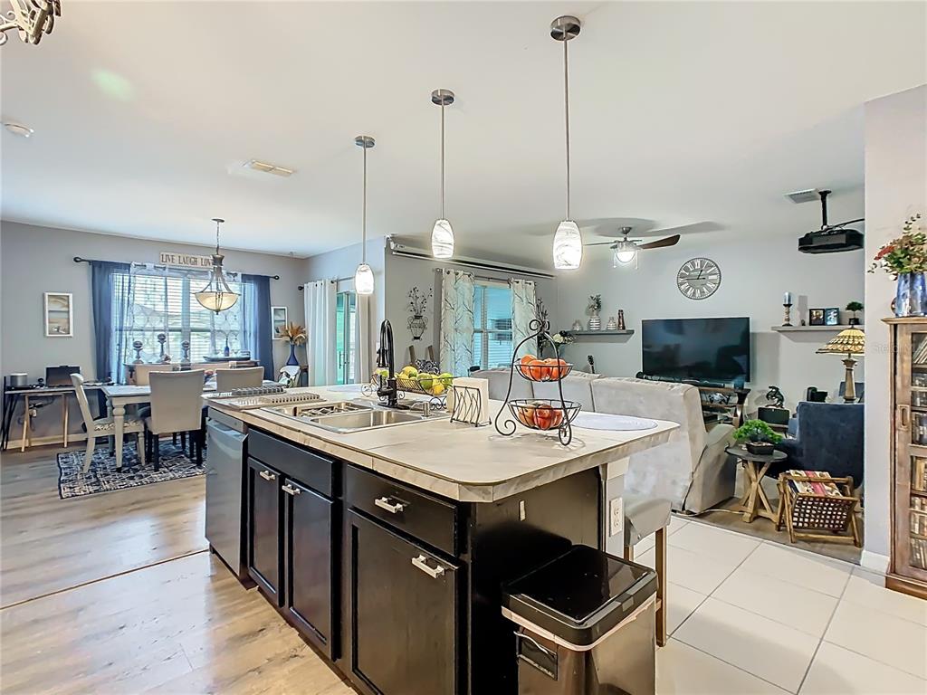 A kitchen island with dark cabinets and a sink sits in an open-concept living space — 1765 BROCKRIDGE ROAD, KISSIMMEE, FL