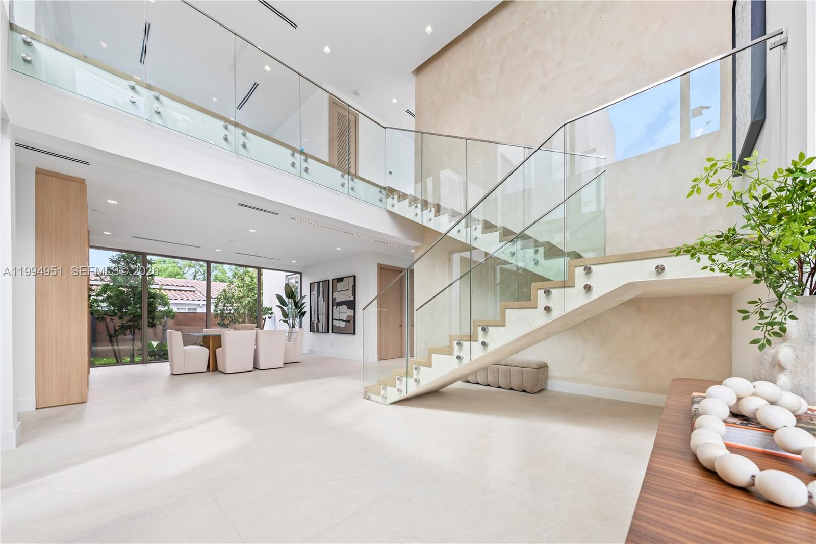 A modern, open-concept living area features a glass-railed staircase and large windows — 4125 NW 5th Ave, Miami FL 33127, MIAMI, FL