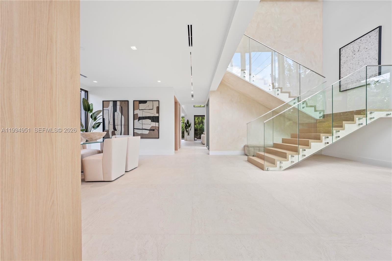 A modern, minimalist living area features a floating wooden staircase with glass railings — 4125 NW 5th Ave, Miami FL 33127, MIAMI, FL