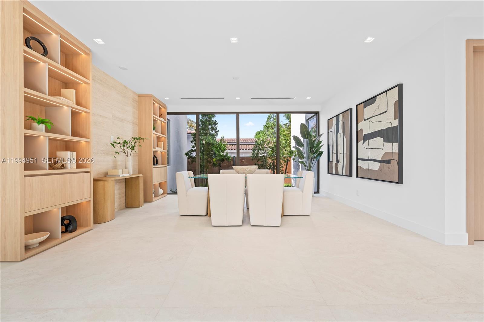 A modern dining room features a glass table, upholstered chairs, built-in shelving, and large windows — 4125 NW 5th Ave, Miami FL 33127, MIAMI, FL