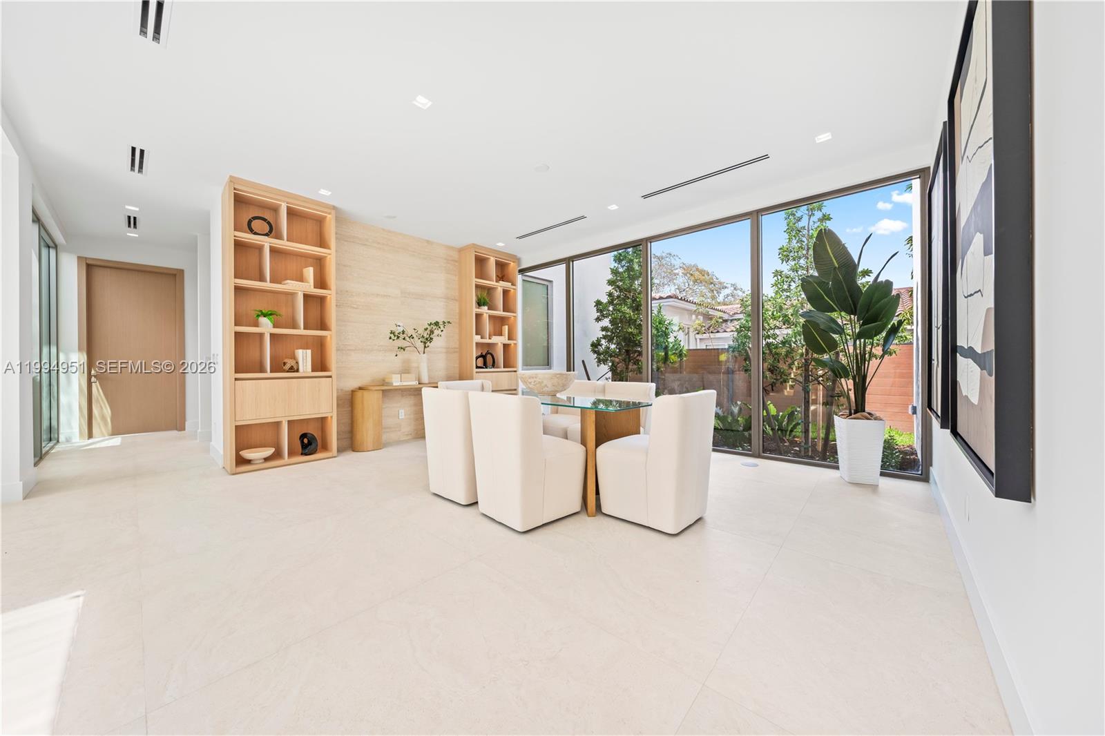 A dining room features a glass table, upholstered chairs, built-in shelving, and floor-to-ceiling windows — 4125 NW 5th Ave, Miami FL 33127, MIAMI, FL