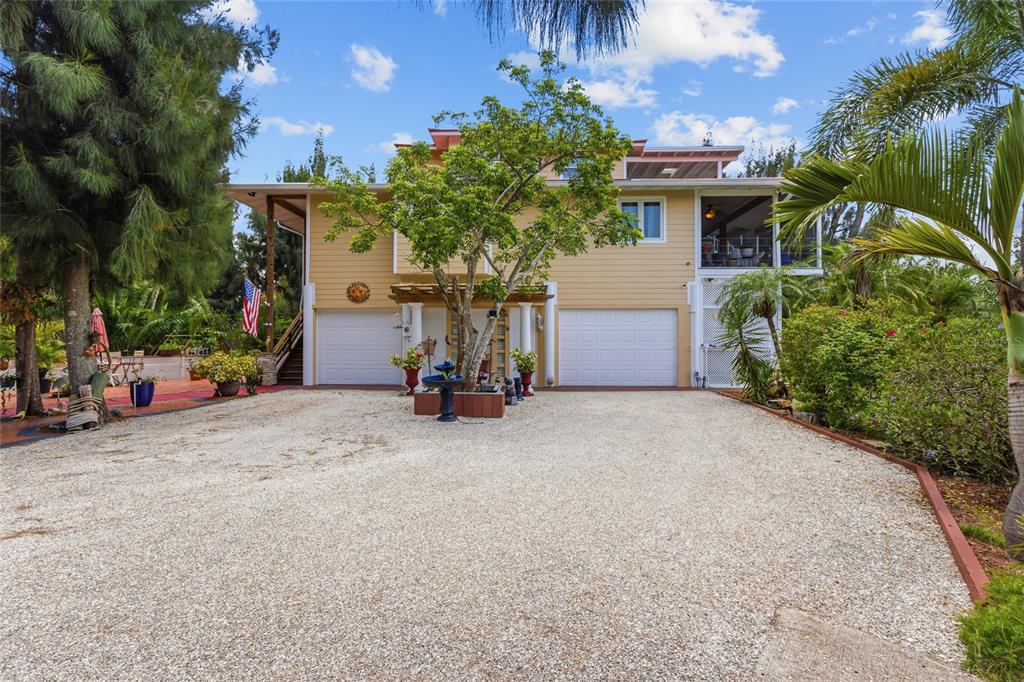 A two-story house with a gravel driveway, two garage doors, and a central tree — 10007 TAMIAMI TRAIL S, NORTH PORT, FL