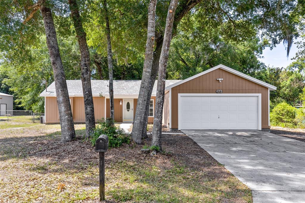 A single-story house with brown vertical siding, a white garage door, and a front yard — 45 LAKE DRIVE, DEBARY, FL