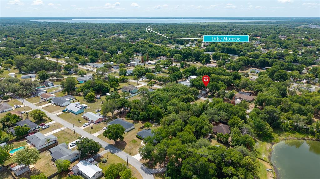 An aerial view shows a residential neighborhood with houses, trees, and a nearby lake — 45 LAKE DRIVE, DEBARY, FL