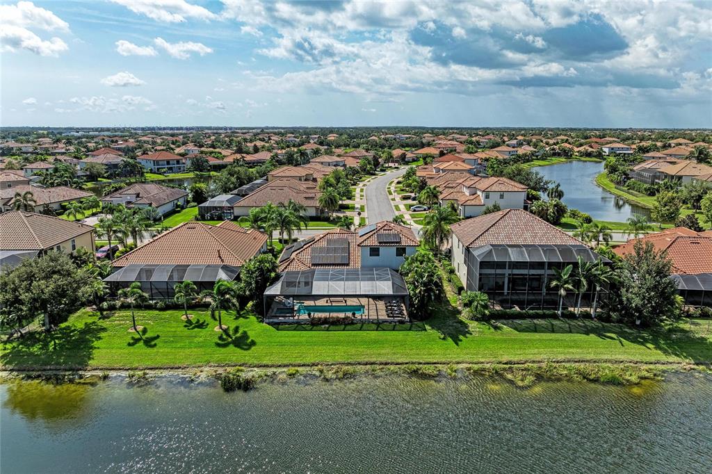 An aerial view shows several suburban houses with screened-in pools along a lake — 5664 CLOVERLEAF RUN, LAKEWOOD RANCH, FL
