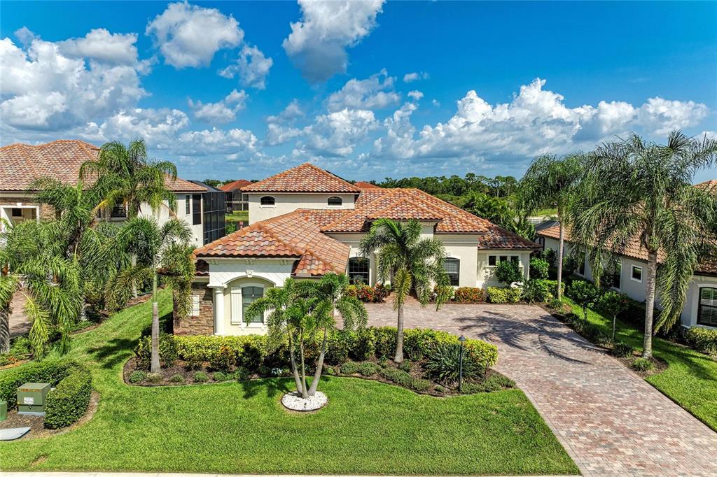 A single-story house with a tiled roof and a brick driveway sits on a lawn — 5664 CLOVERLEAF RUN, LAKEWOOD RANCH, FL