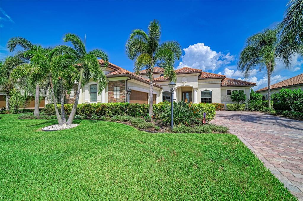 A single-story house with a tiled roof, stone accents, and a paved driveway — 5664 CLOVERLEAF RUN, LAKEWOOD RANCH, FL