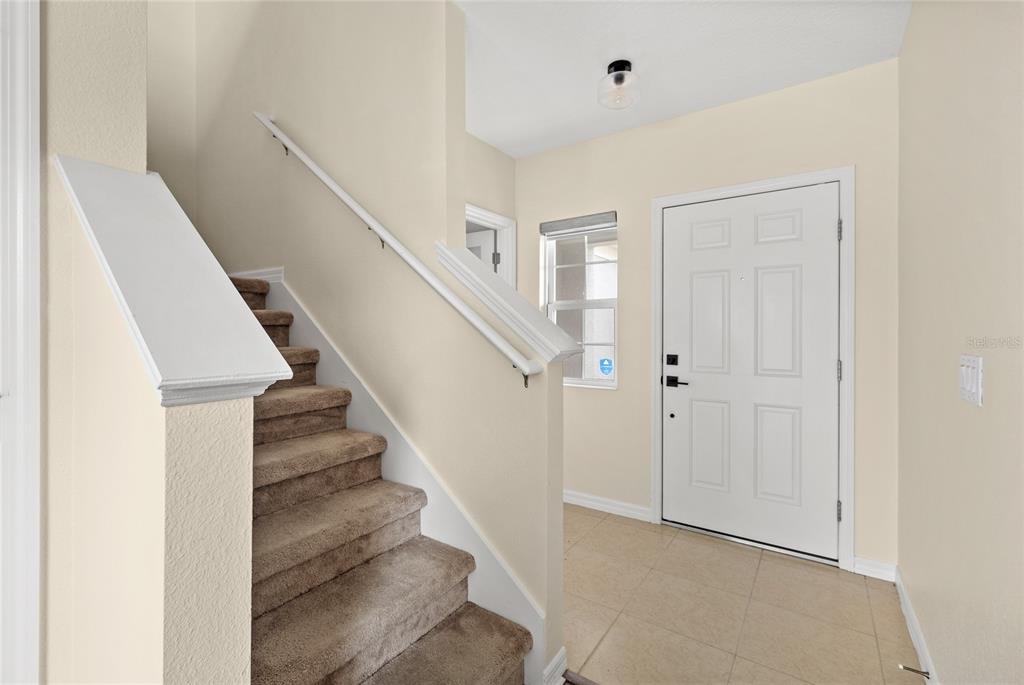 An entryway features a carpeted staircase with a white railing and a white front door — 922 ANNA PLACE, DAVENPORT, FL