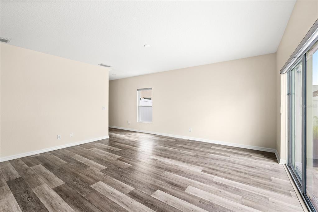 An empty room with light-colored walls, wood-look flooring, a single window, and sliding glass doors — 922 ANNA PLACE, DAVENPORT, FL
