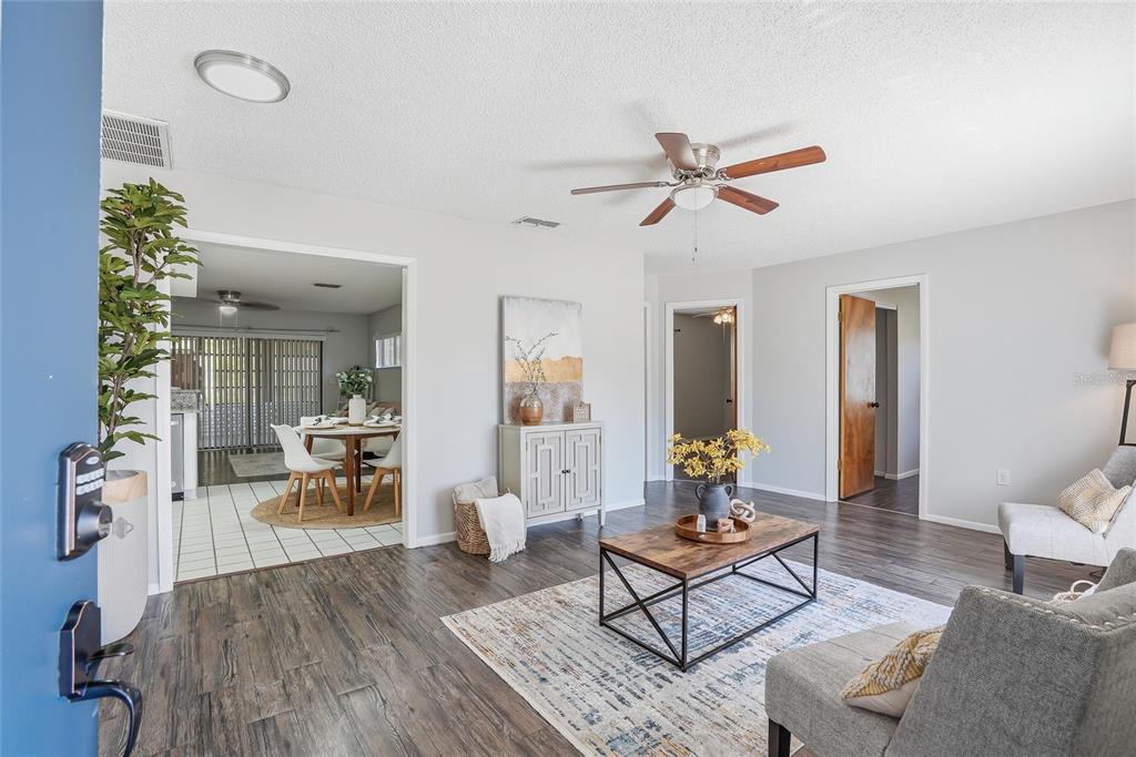 A living room with wood-look flooring, a ceiling fan, and an adjacent dining area — 3276 MORVEN DRIVE, SPRING HILL, FL