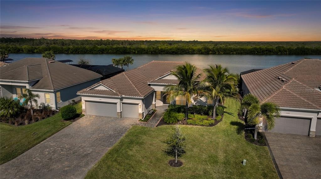 An aerial view of a suburban house with a tile roof, driveway, and waterfront backyard — 15240 SPANISH POINT DRIVE, PORT CHARLOTTE, FL