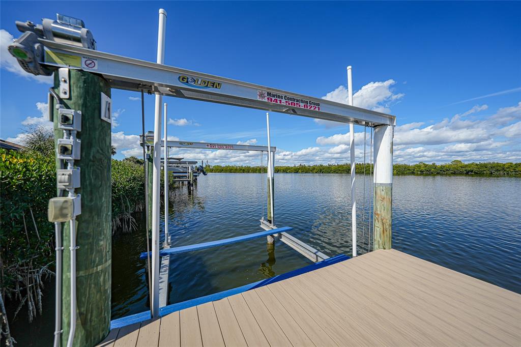 A boat lift stands over a canal next to a wooden dock — 15240 SPANISH POINT DRIVE, PORT CHARLOTTE, FL