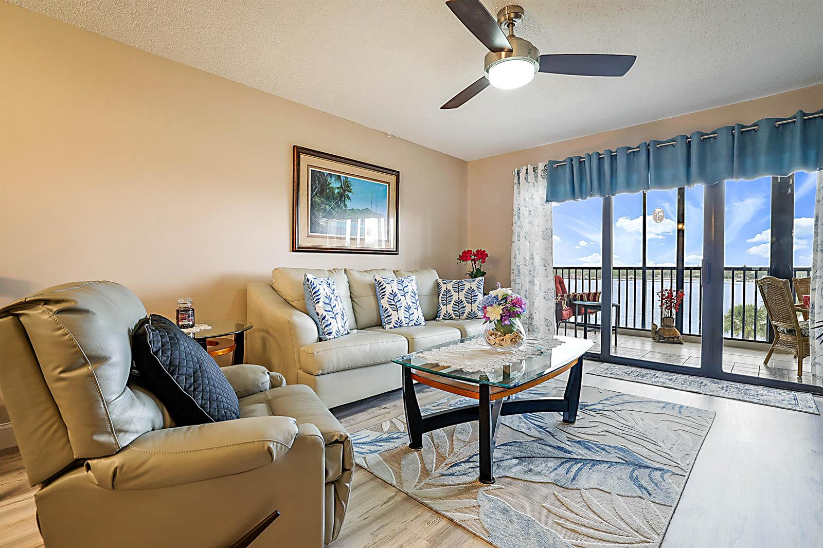A living room features a beige sofa, a recliner, a glass coffee table, and balcony access — 300 Intracoastal Place # 403, Jupiter FL 33469, JUPITER, FL