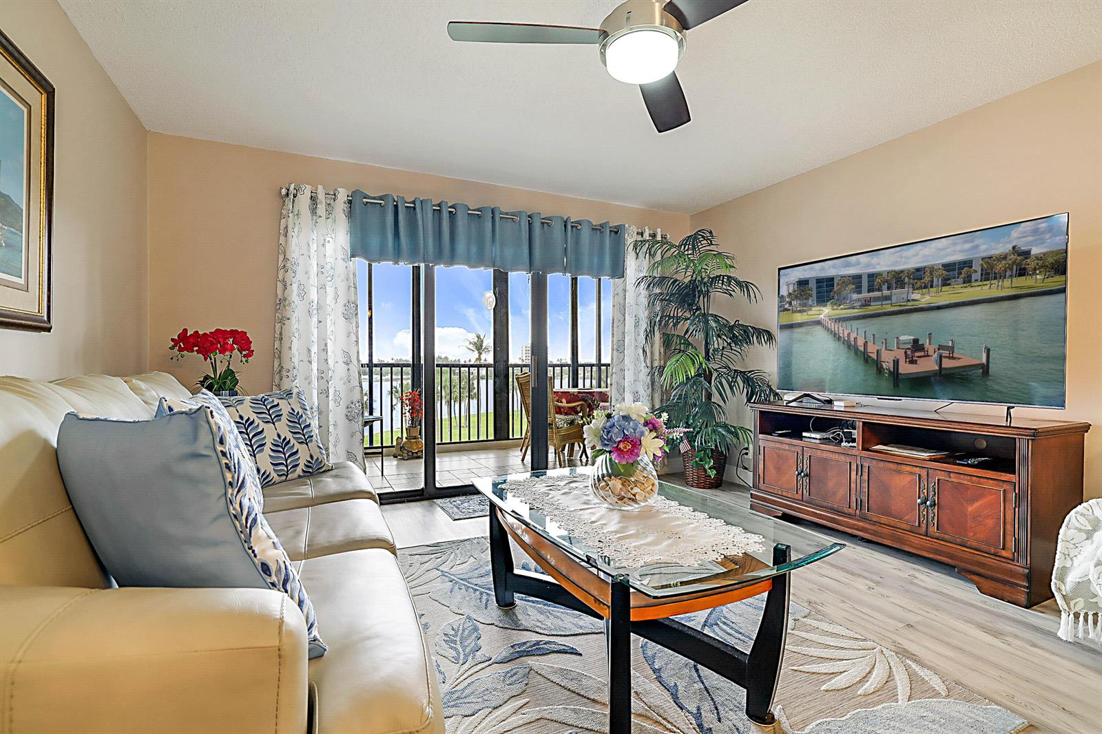 A living room features a leather sofa, glass coffee table, television, and a balcony view — 300 Intracoastal Place # 403, Jupiter FL 33469, JUPITER, FL