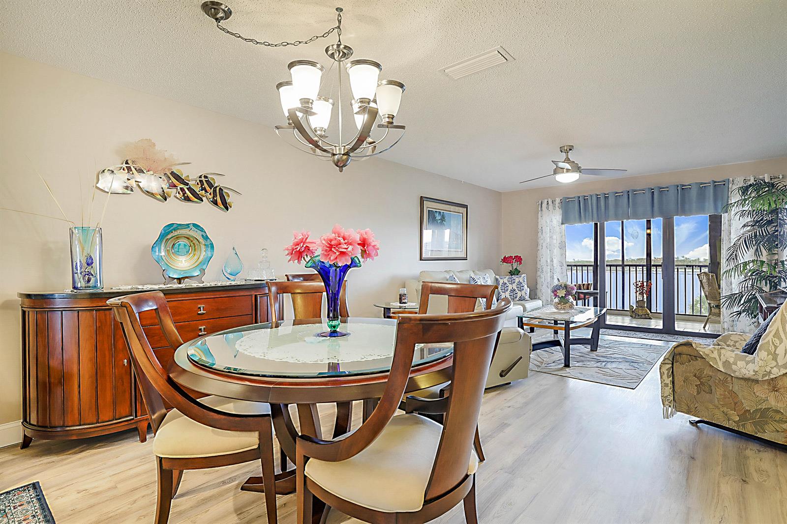 A dining area with a glass-top table and a living room overlooking a waterfront balcony — 300 Intracoastal Place # 403, Jupiter FL 33469, JUPITER, FL