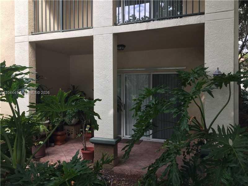 A ground-level patio with tiled flooring, potted plants, and sliding glass doors — 2464 Centergate Dr # 101, Miramar FL 33025, MIRAMAR, FL