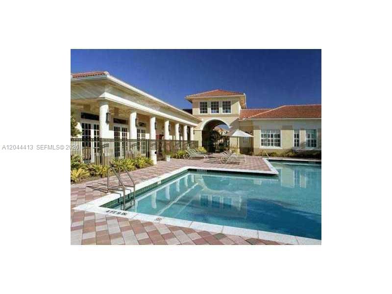 A swimming pool sits in front of a building with a covered walkway and columns — 2464 Centergate Dr # 101, Miramar FL 33025, MIRAMAR, FL