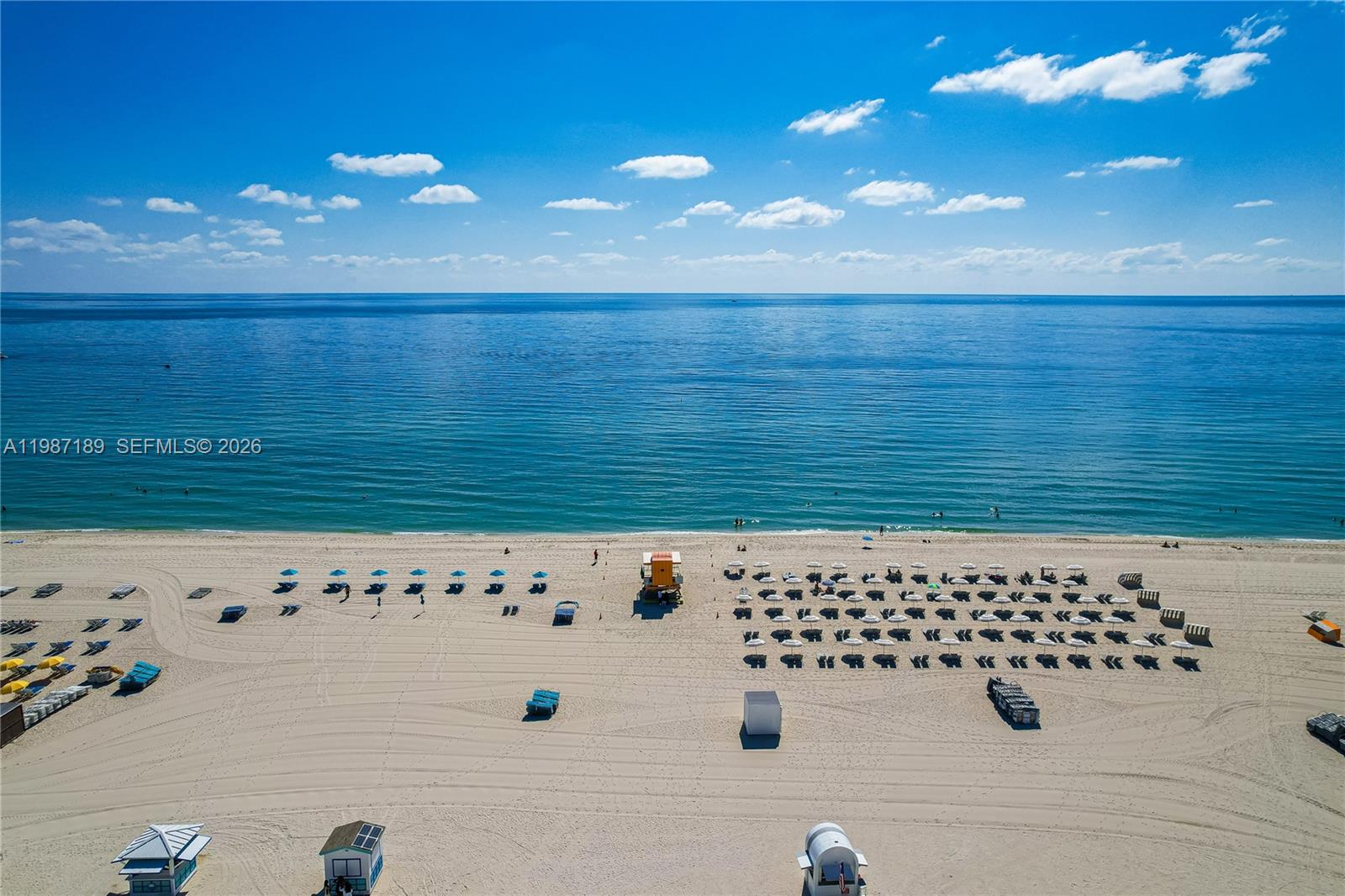 An aerial view shows a sandy beach with rows of umbrellas, lounge chairs, and lifeguard stands — 1500 Ocean Dr # 505, Miami Beach FL 33139, MIAMI BEACH, FL