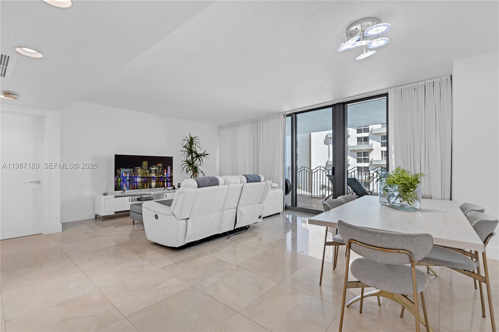 A bright living and dining area features white tile floors, modern furniture, and a balcony — 1500 Ocean Dr # 505, Miami Beach FL 33139, MIAMI BEACH, FL