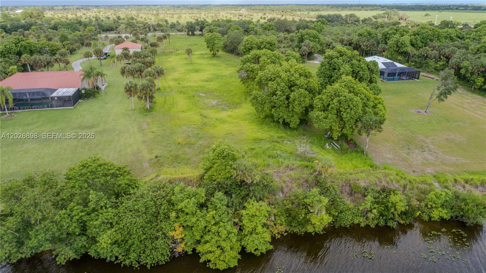 An aerial view shows a grassy lot situated between two houses near a body of water — 5220 Fort Denuad, La Belle FL 33935, LA BELLE, FL