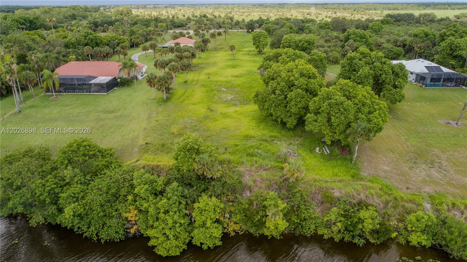 An aerial view shows a grassy lot situated between two houses near a body of water — 5220 Fort Denuad, La Belle FL 33935, LA BELLE, FL