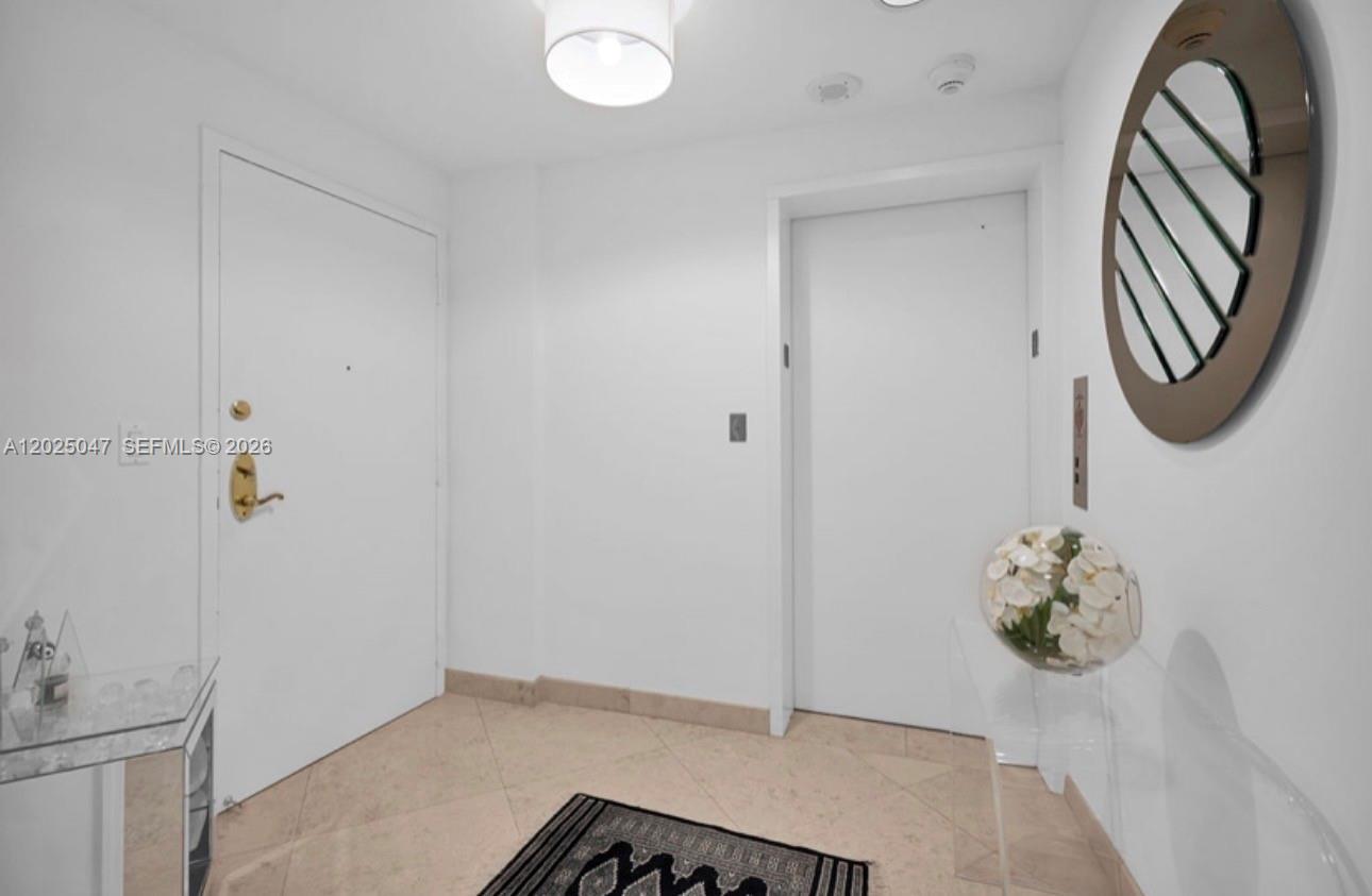 A bright entryway features white walls, tile flooring, a round mirror, and two white doors — 9601 Collins Ave # 403, Bal Harbour FL 33154, BAL HARBOUR, FL