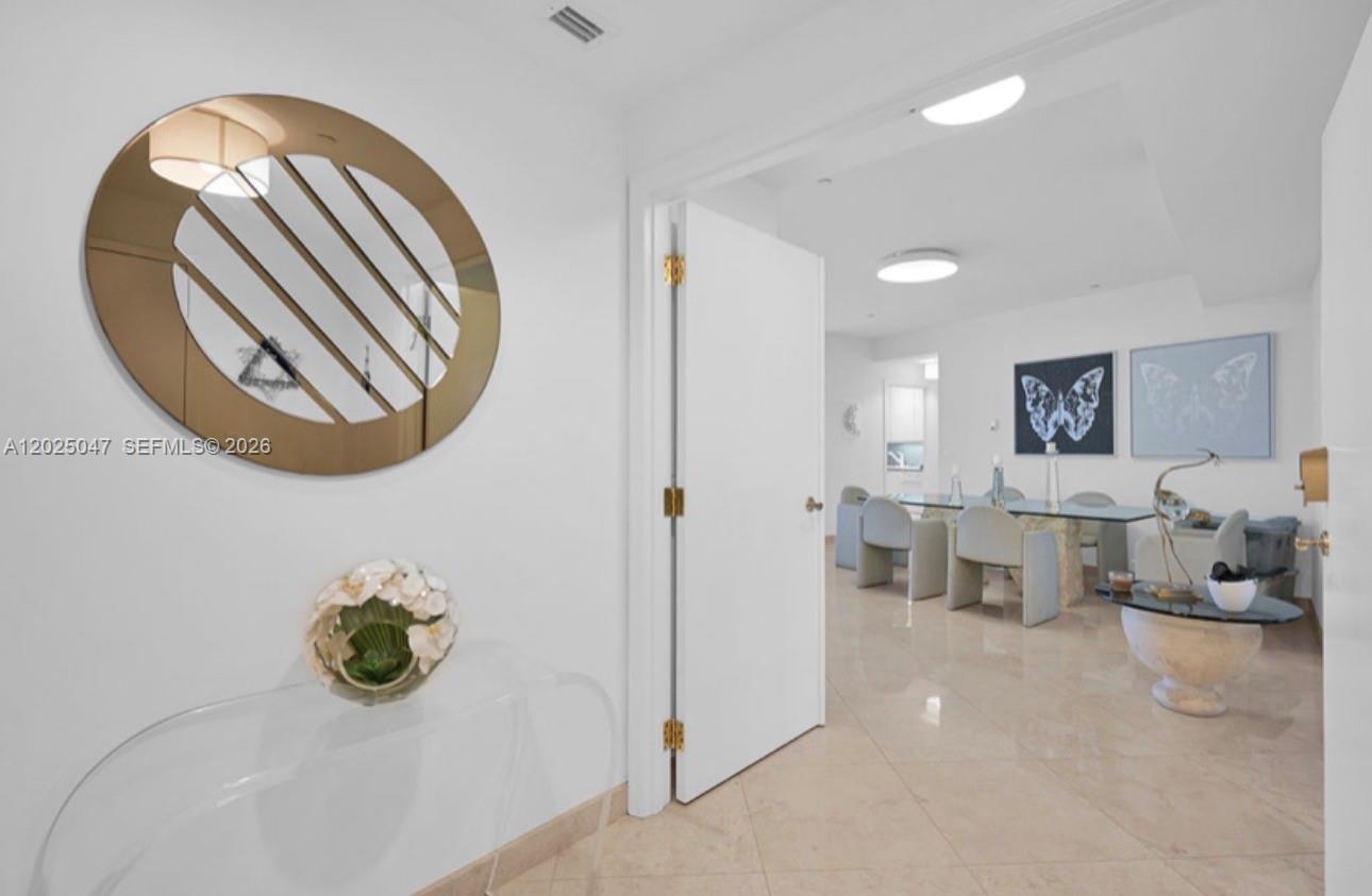 A foyer with a circular mirror and console table leads into a dining room — 9601 Collins Ave # 403, Bal Harbour FL 33154, BAL HARBOUR, FL
