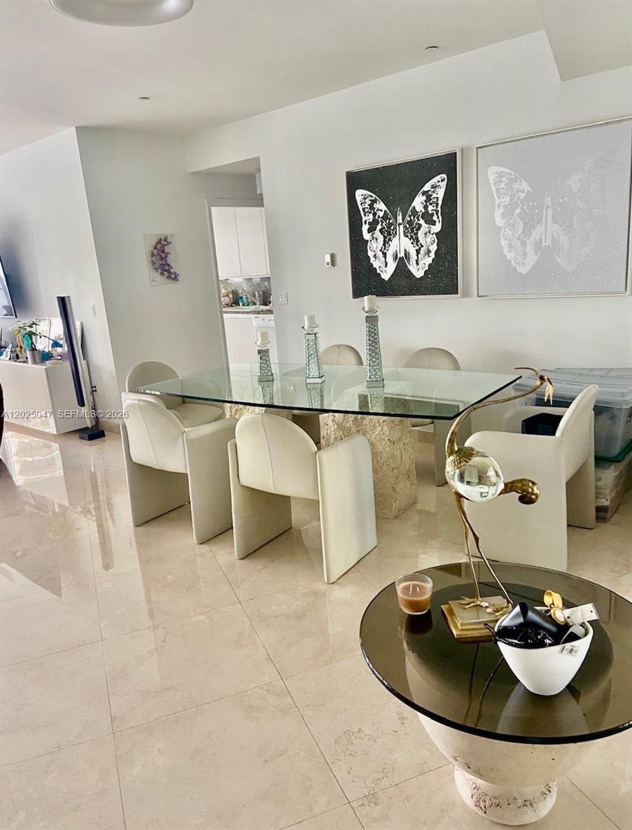 A dining room features a glass-topped table, white chairs, and butterfly wall art — 9601 Collins Ave # 403, Bal Harbour FL 33154, BAL HARBOUR, FL