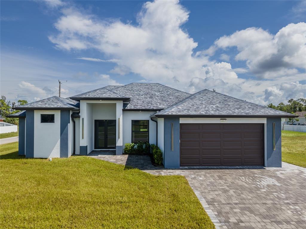 A single-story house with a gray shingled roof, white stucco walls, and a two-car garage — 1817 KISMET PARKWAY W, CAPE CORAL, FL