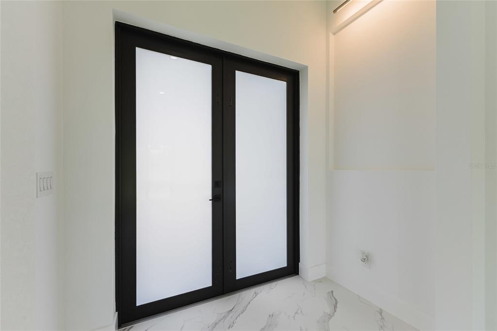 A set of black-framed double doors with frosted glass panels sits in a white room — 1817 KISMET PARKWAY W, CAPE CORAL, FL