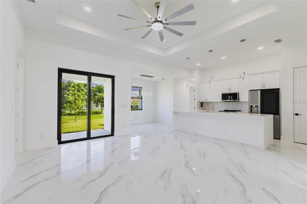 A bright, open-concept kitchen and living area features white marble floors and a tray ceiling — 1817 KISMET PARKWAY W, CAPE CORAL, FL