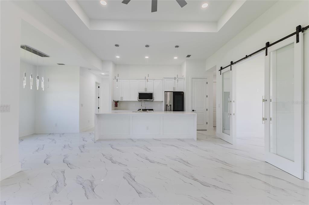 A modern kitchen features white cabinetry, a large island, and marble-patterned tile flooring — 1817 KISMET PARKWAY W, CAPE CORAL, FL