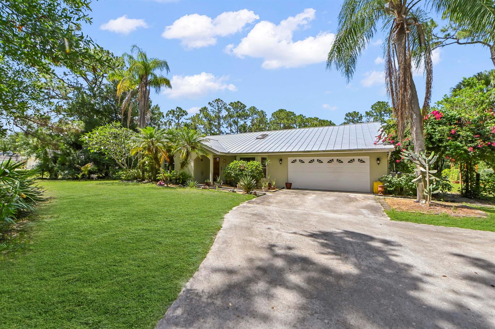 A single-story house with a metal roof, a two-car garage, and a large front lawn — 12369 157th Street N, Jupiter FL 33478, JUPITER, FL