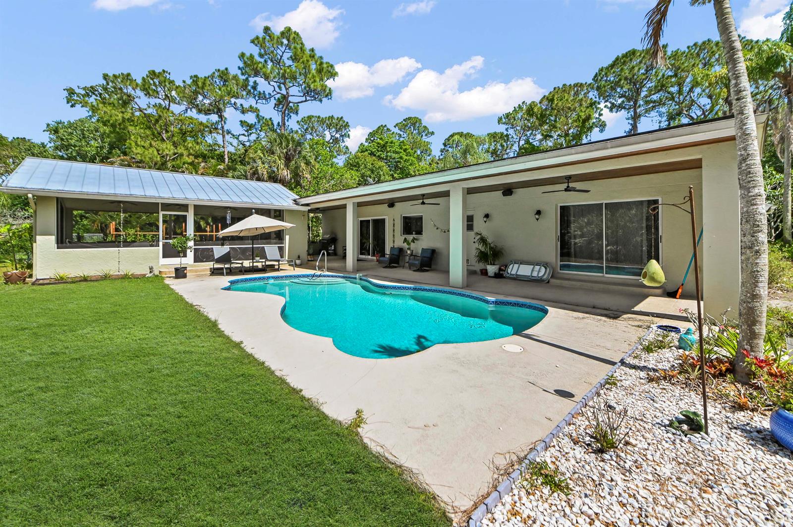 A backyard features a swimming pool, a covered patio, and a screened-in porch area — 12369 157th Street N, Jupiter FL 33478, JUPITER, FL