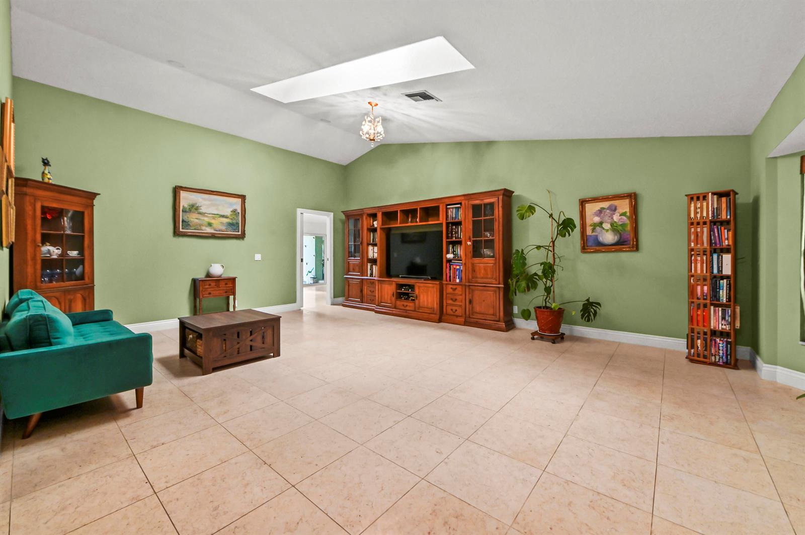 A spacious living room features green walls, tile flooring, a large entertainment center, and furniture — 12369 157th Street N, Jupiter FL 33478, JUPITER, FL
