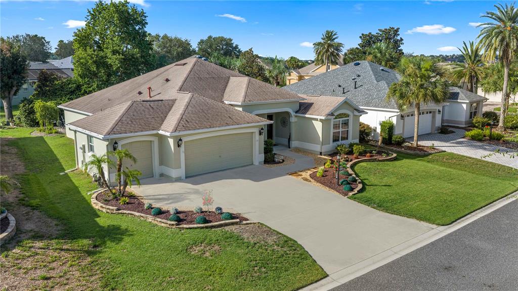 An aerial view of a single-story suburban house with a tan exterior and concrete driveway — 346 PACOLET TERRACE, THE VILLAGES, FL
