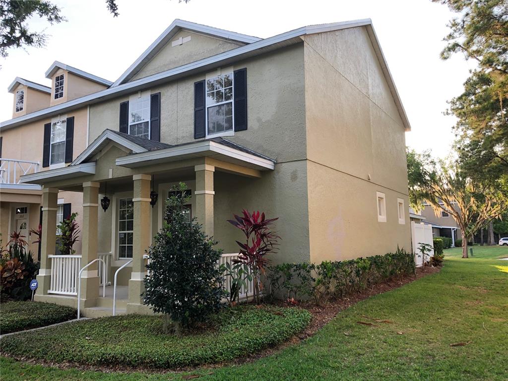 A two-story tan townhouse with a covered front porch and black window shutters — 5567 SOMERSBY ROAD, WINDERMERE, FL