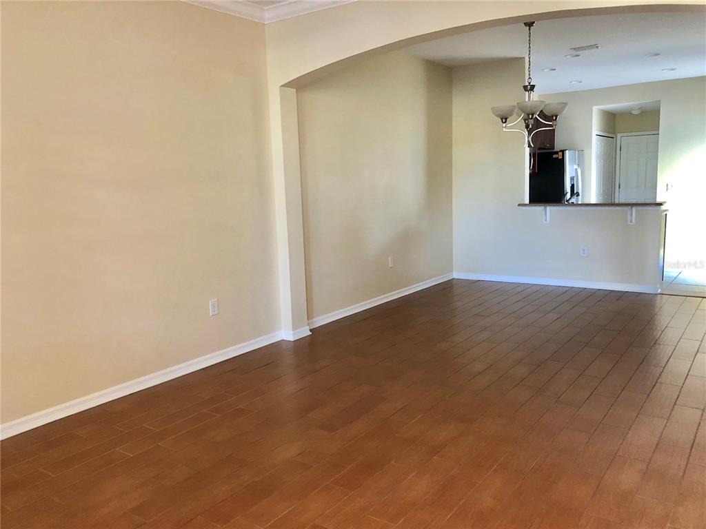 An open living area with wood-look tile flooring leads to a kitchen with a breakfast bar — 5567 SOMERSBY ROAD, WINDERMERE, FL